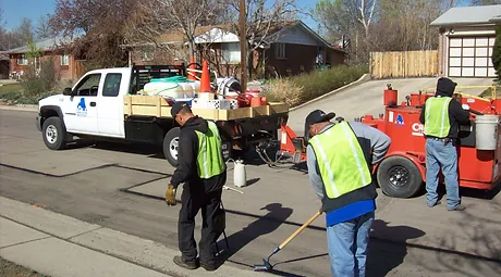 Road Builders Manually Sealing the Crack - Apex Pavement Solutions